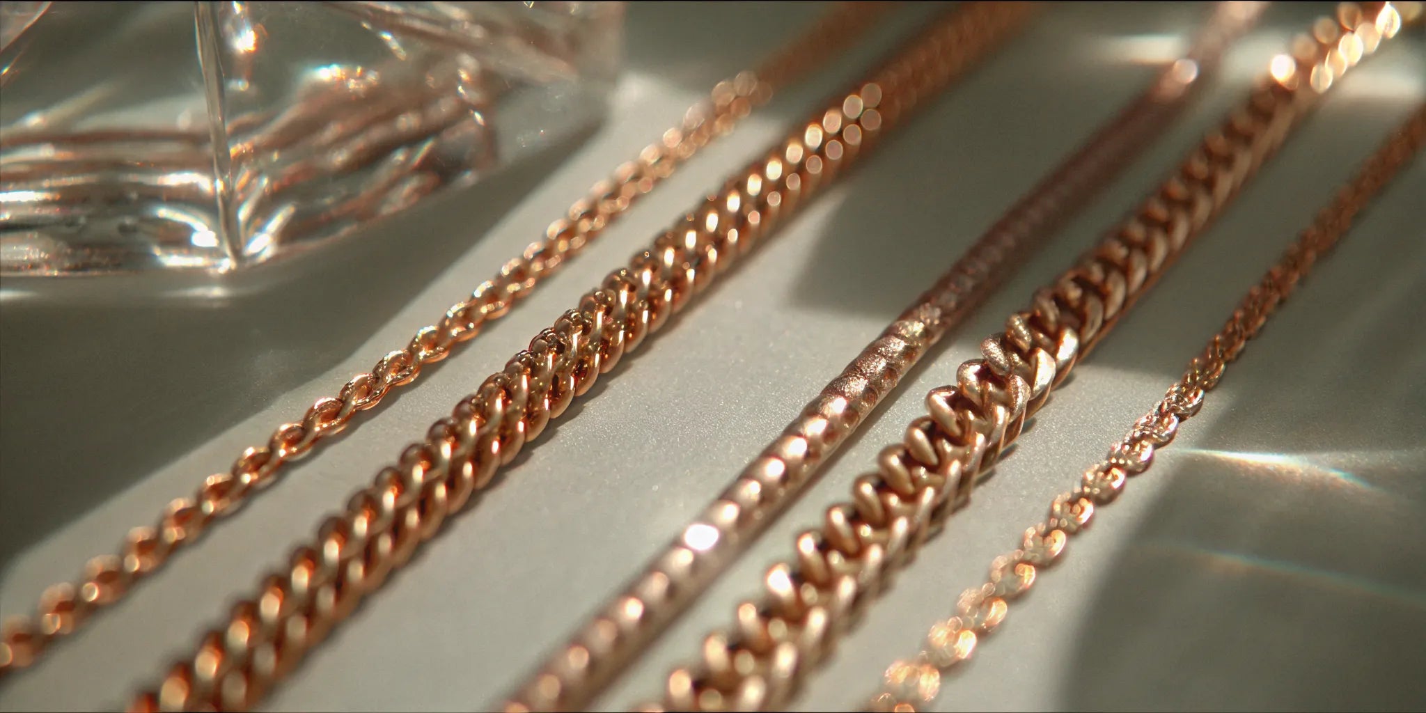 A collection of 14k gold chains for men, featuring Cuban, rope, and Figaro link styles.