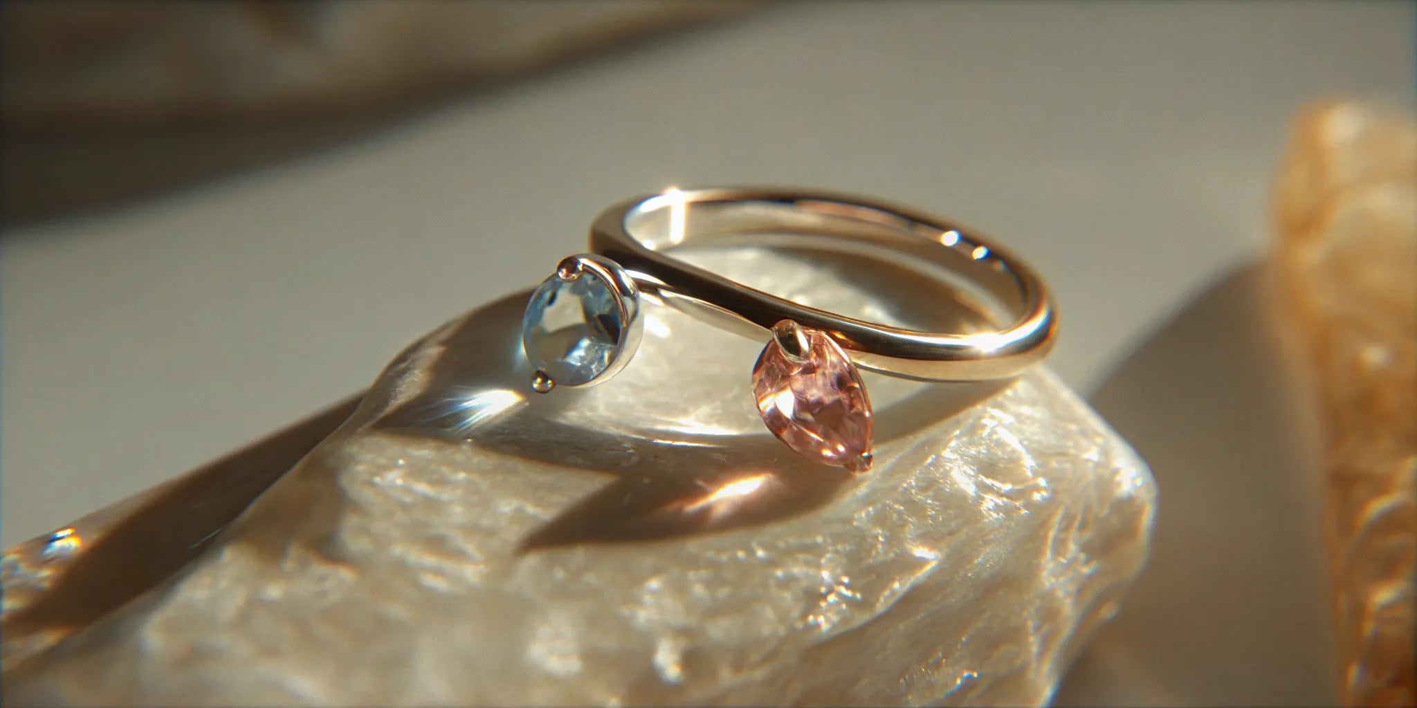 A gold 2 stone birthstone ring with a blue and a pink gemstone.