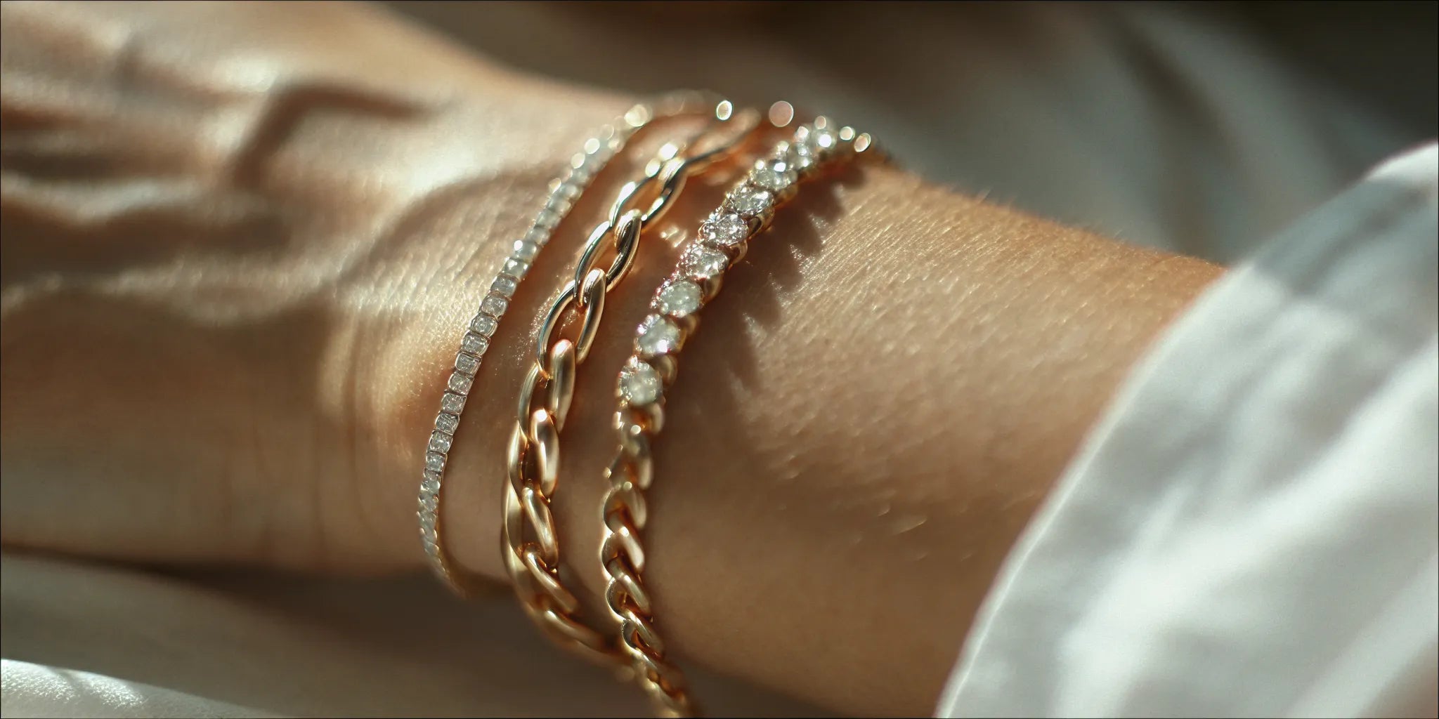 Layered gold chain and diamond bracelets on a wrist