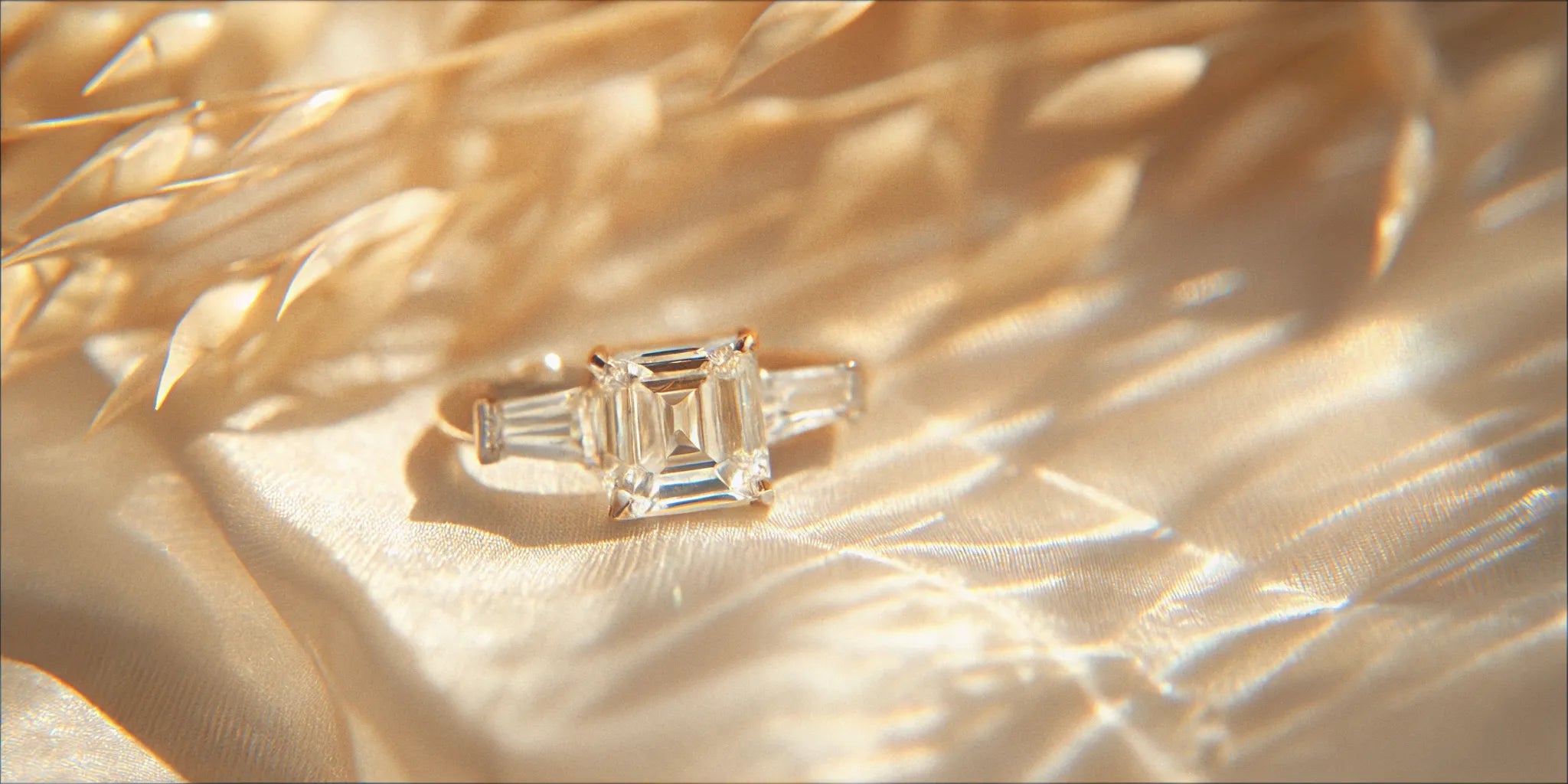 Elegant emerald cut diamond engagement ring in a three-stone setting with tapered baguette side stones