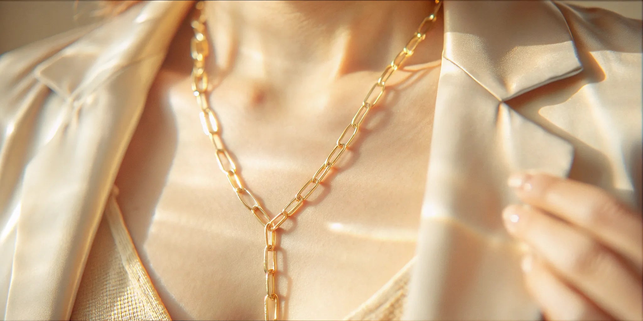 Solid gold lariat necklace with a paperclip chain worn over a blazer.