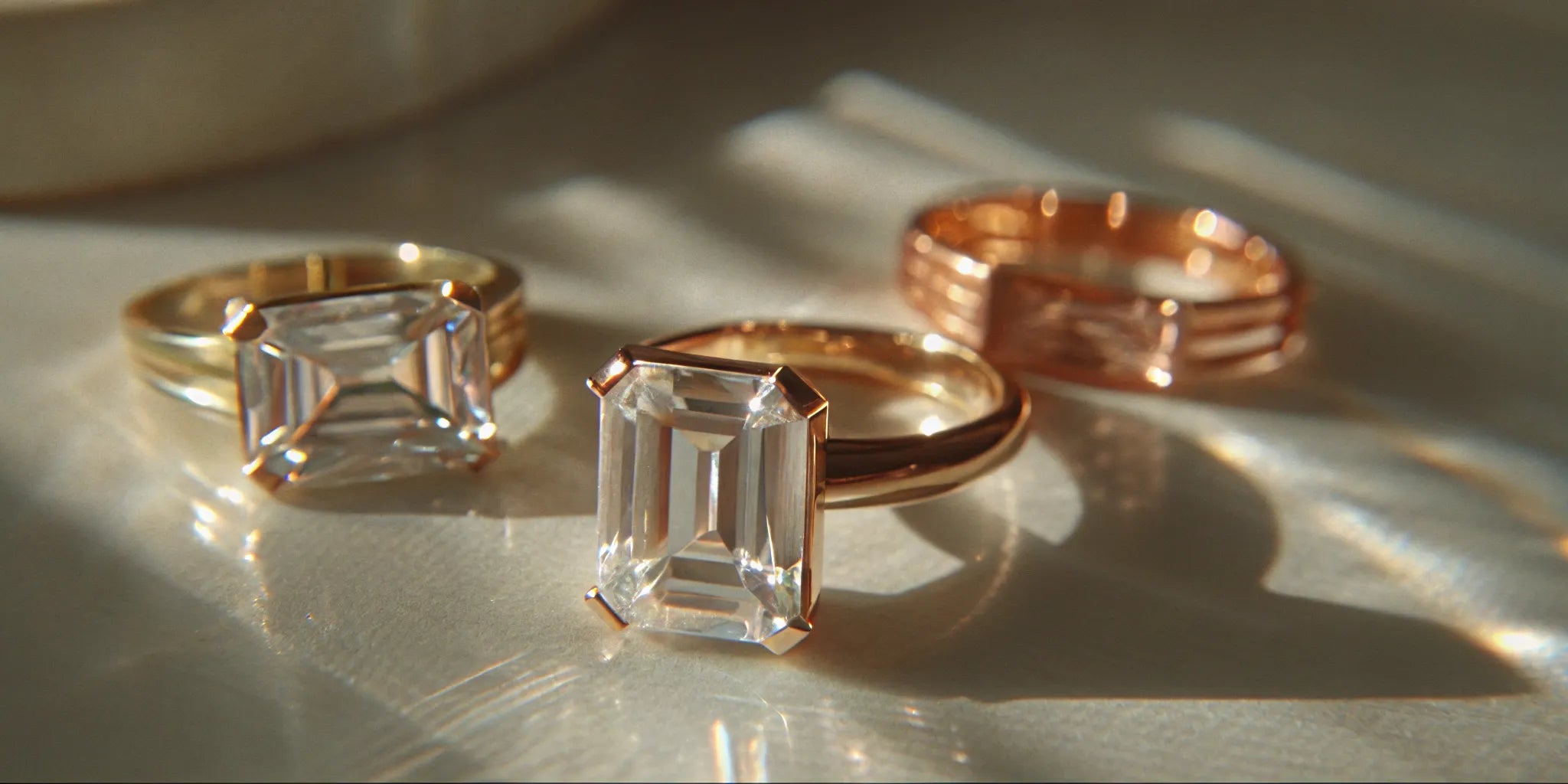 Modern emerald cut diamond engagement rings in yellow gold and rose gold settings.