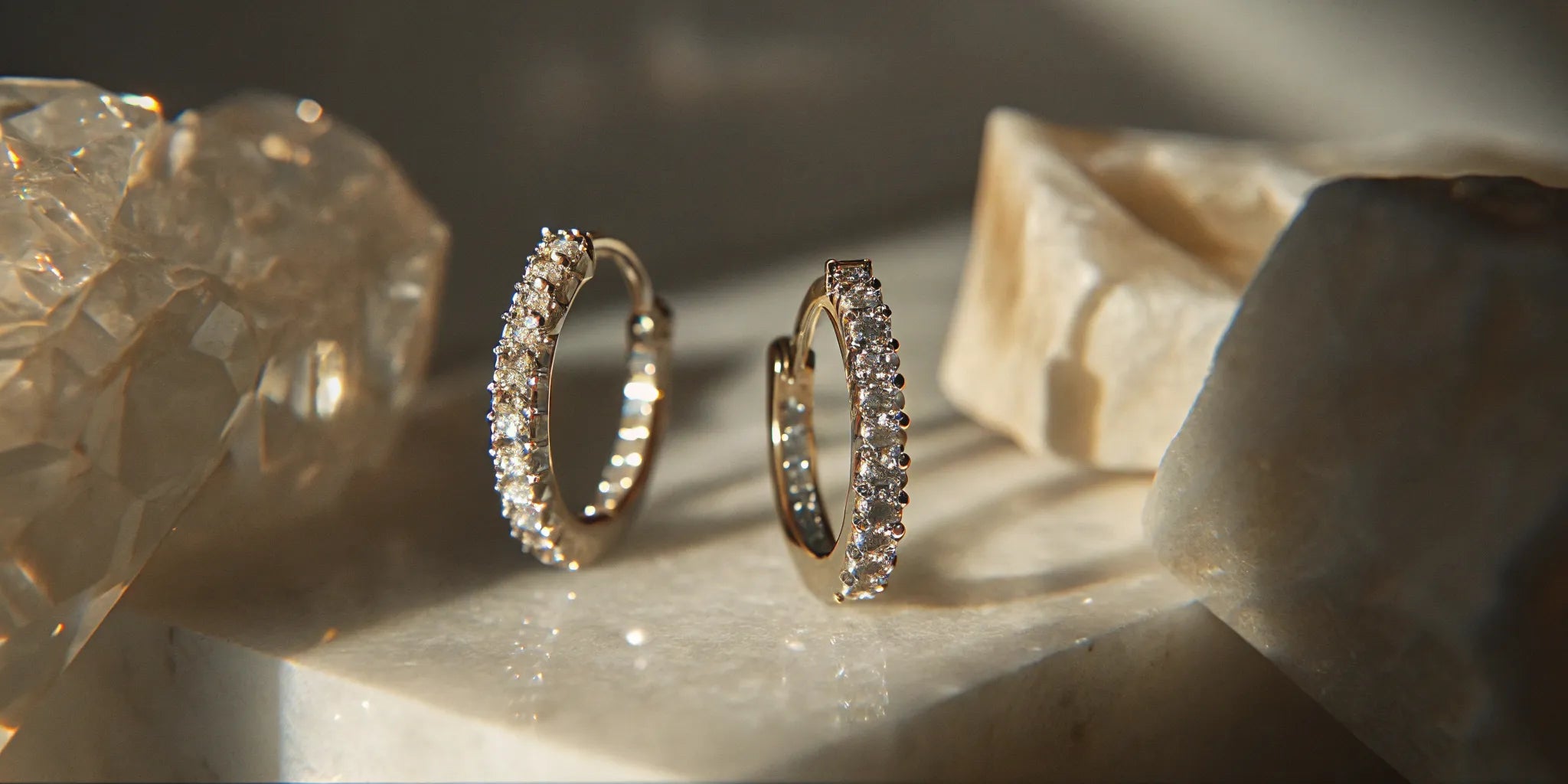 A pair of lab grown diamond huggies with a pavé setting, sparkling on a marble surface.