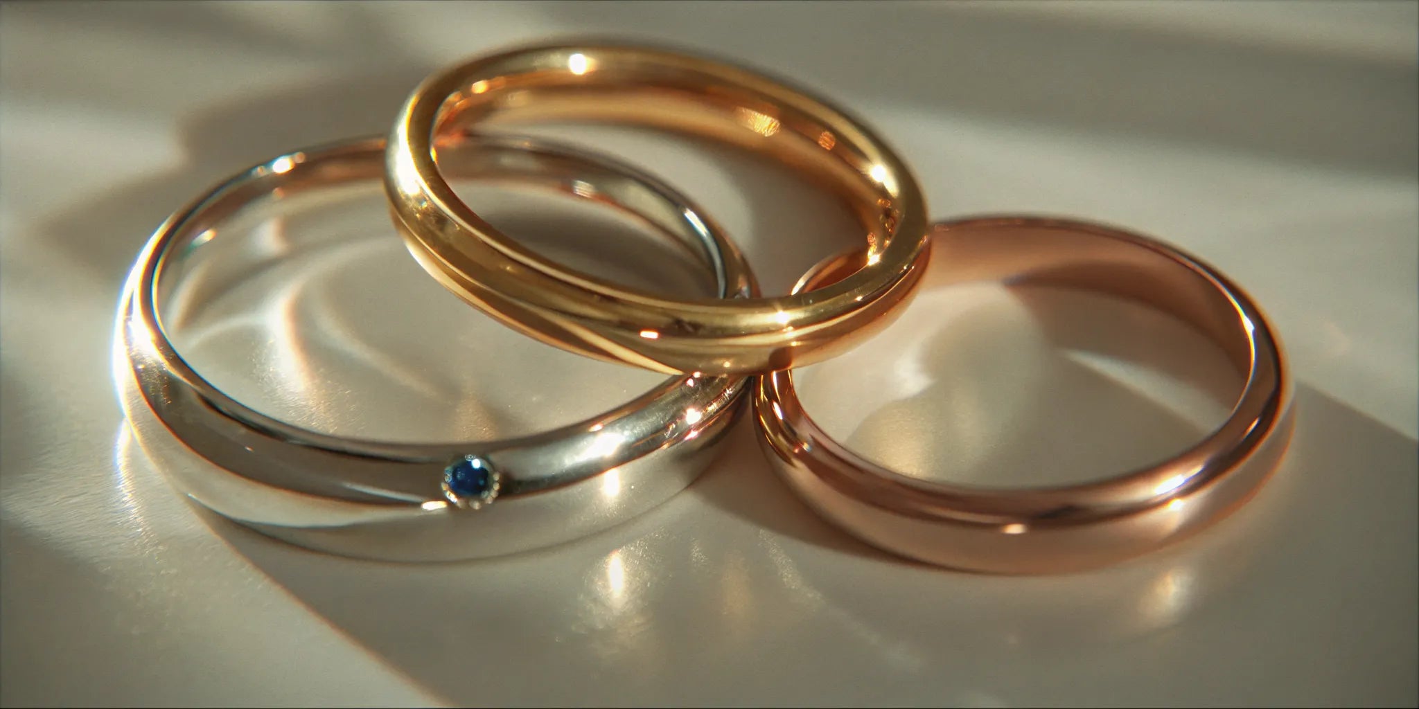 Gold, rose gold, and silver wedding bands, one with a birthstone set inside.