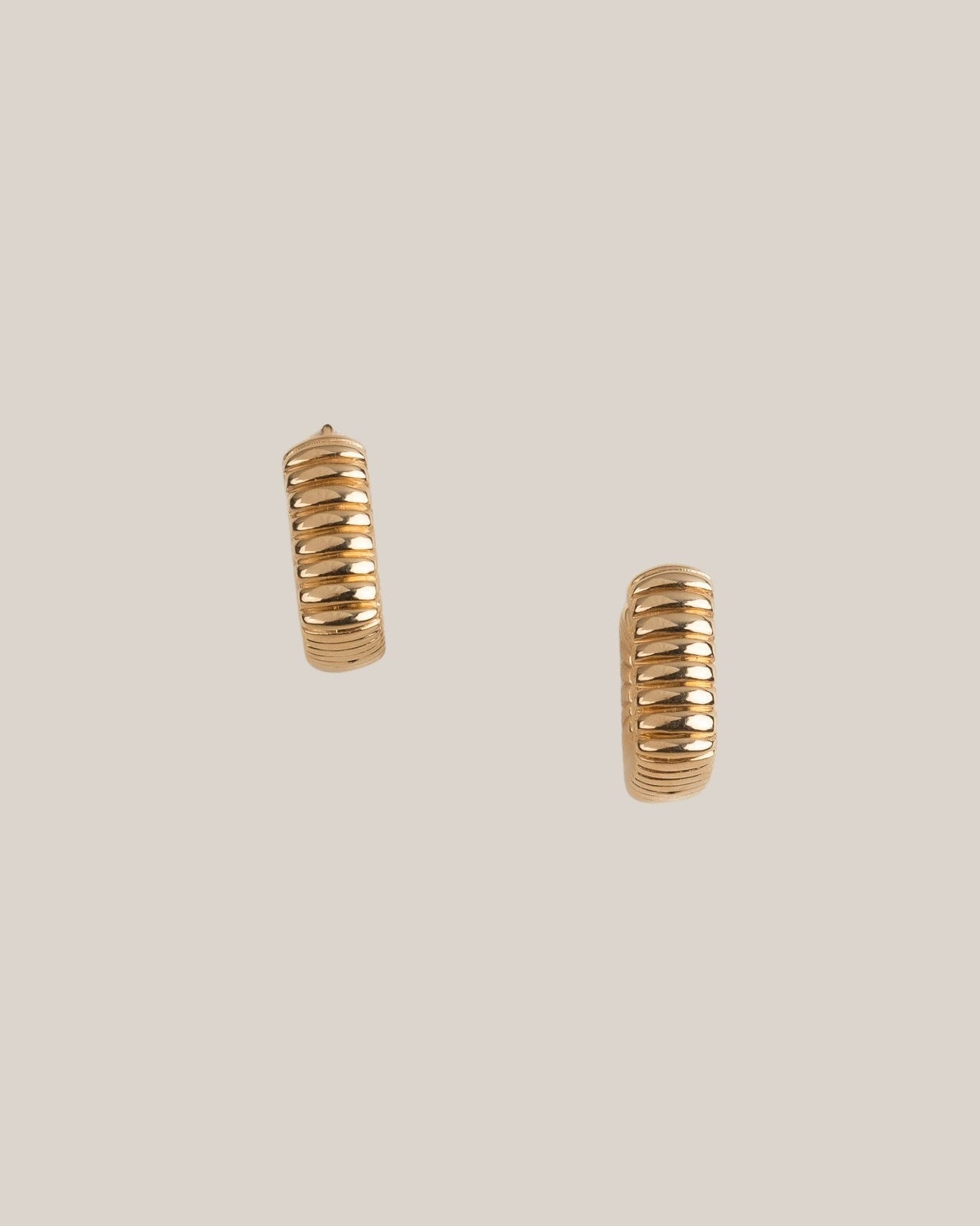 Gold hoop earrings on a beige background