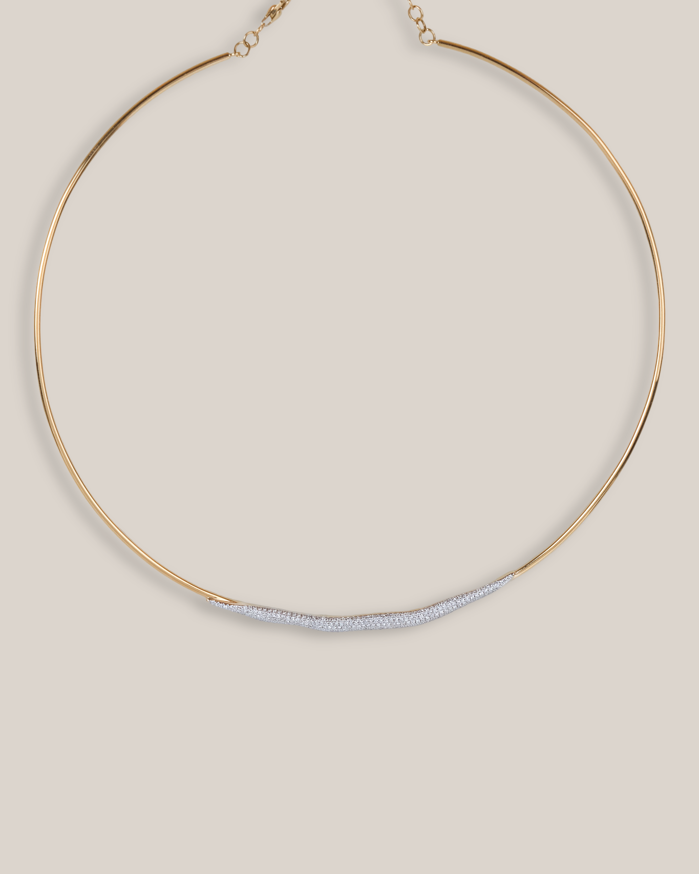A minimalist gold-toned huggie necklace with a textured, silver-toned curved bar across the center, displayed on a solid beige background.