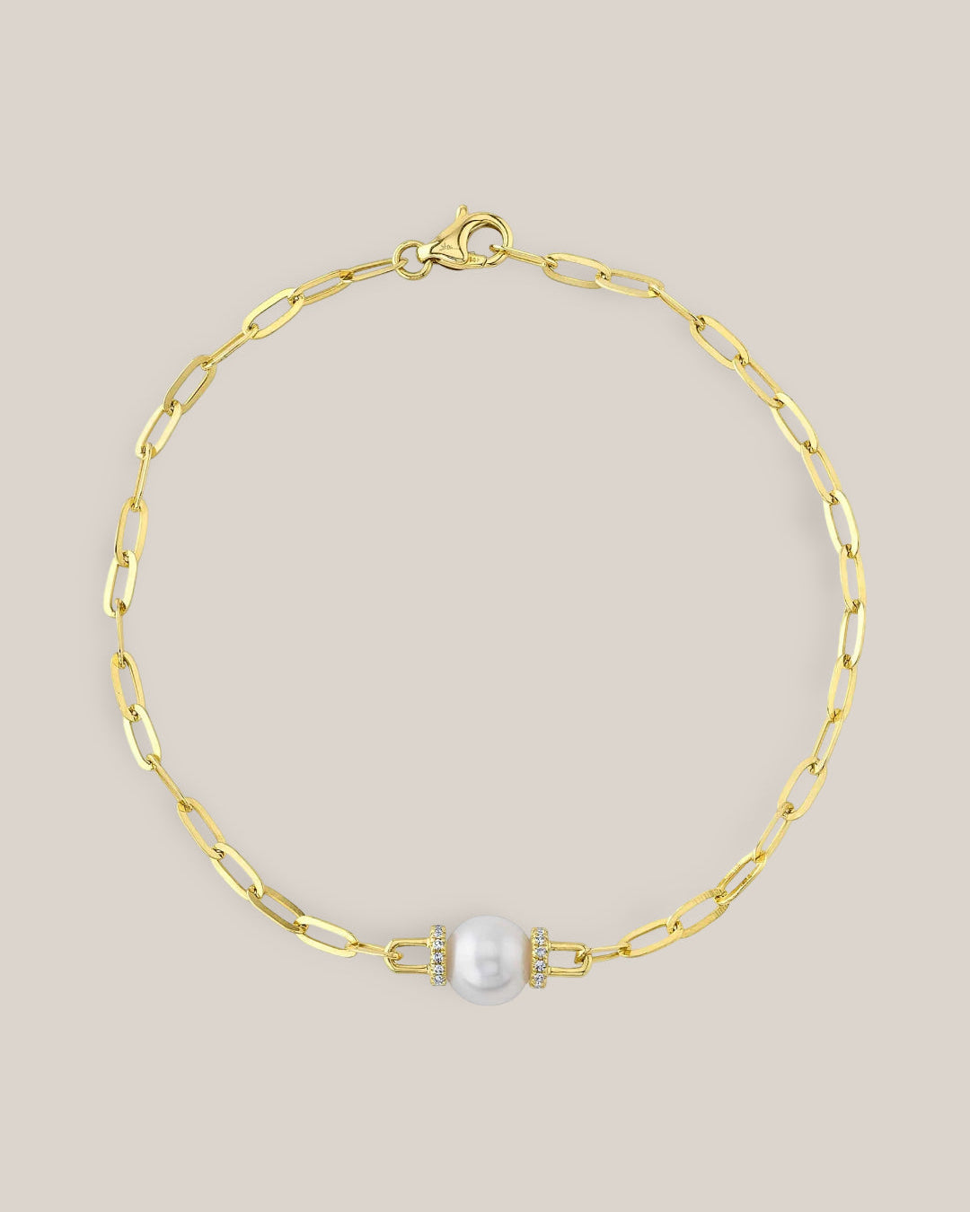 Gold chain bracelet with a pearl and clasp on a beige background