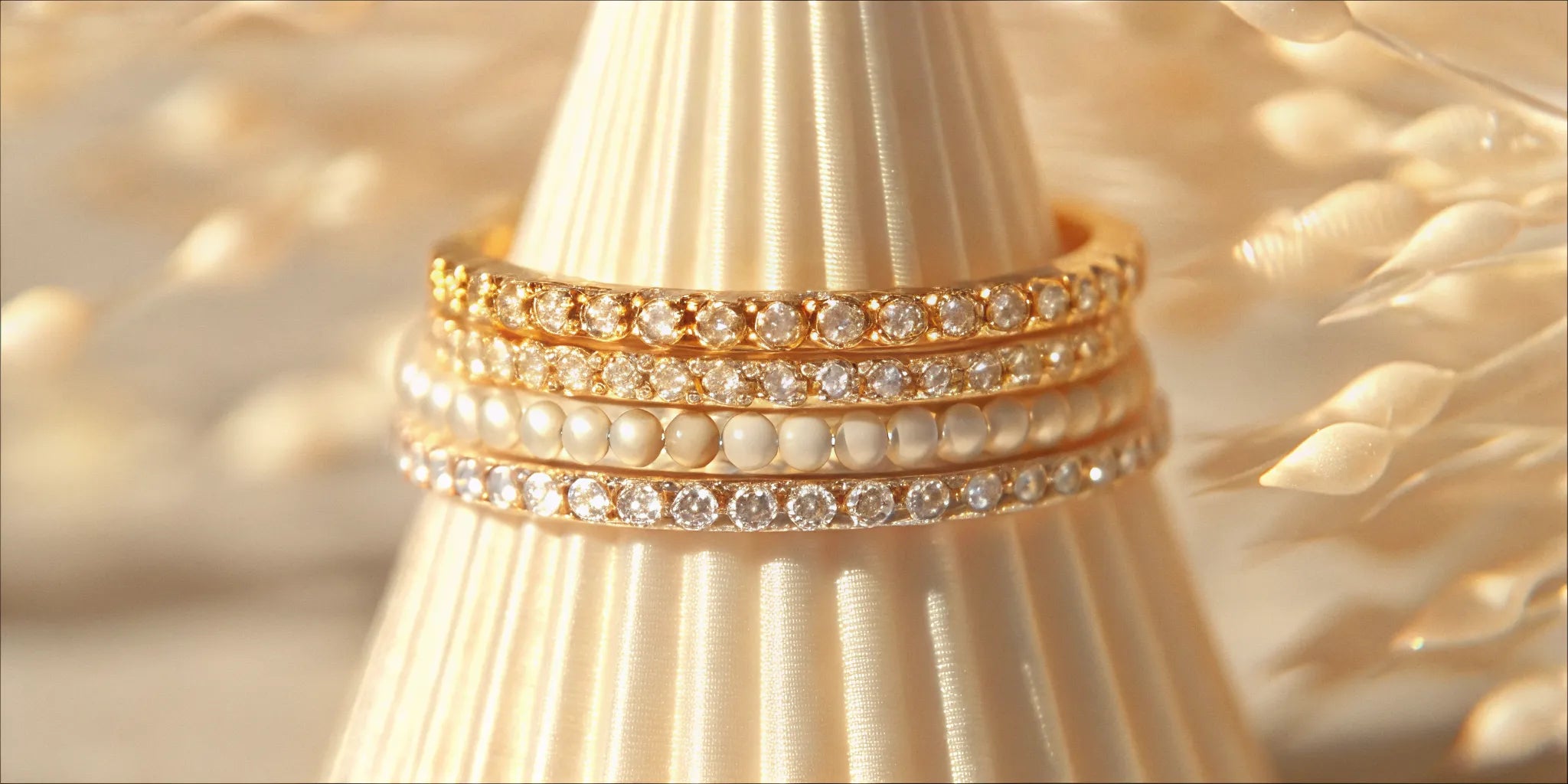Stackable diamond rings for women in gold with pavé and pearl accents.