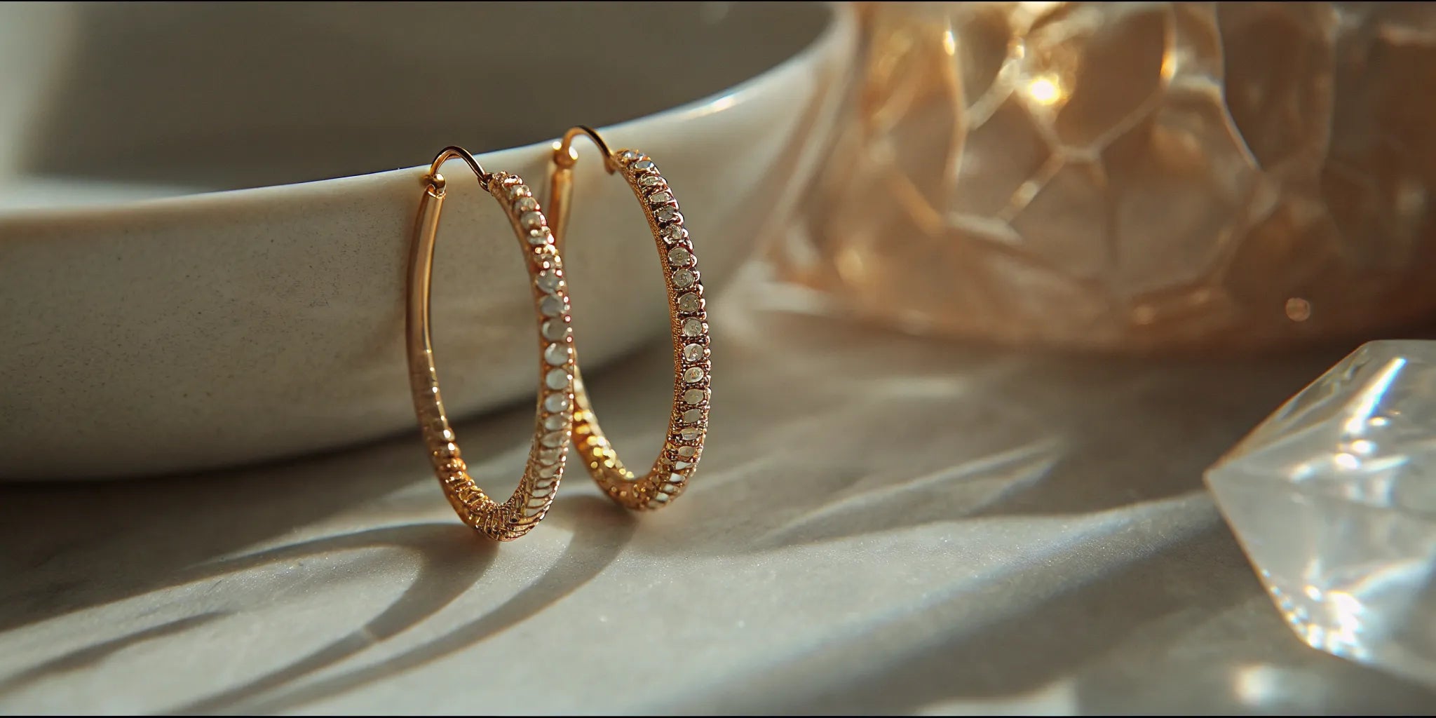 A pair of gold hoop earrings with a detailed pavé setting.