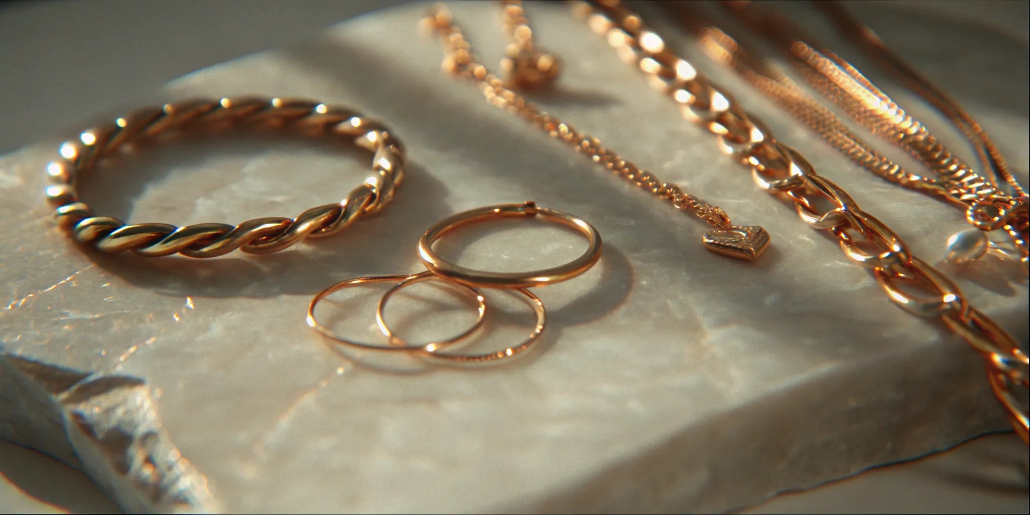 Gold everyday luxury jewelry arranged on pale stone