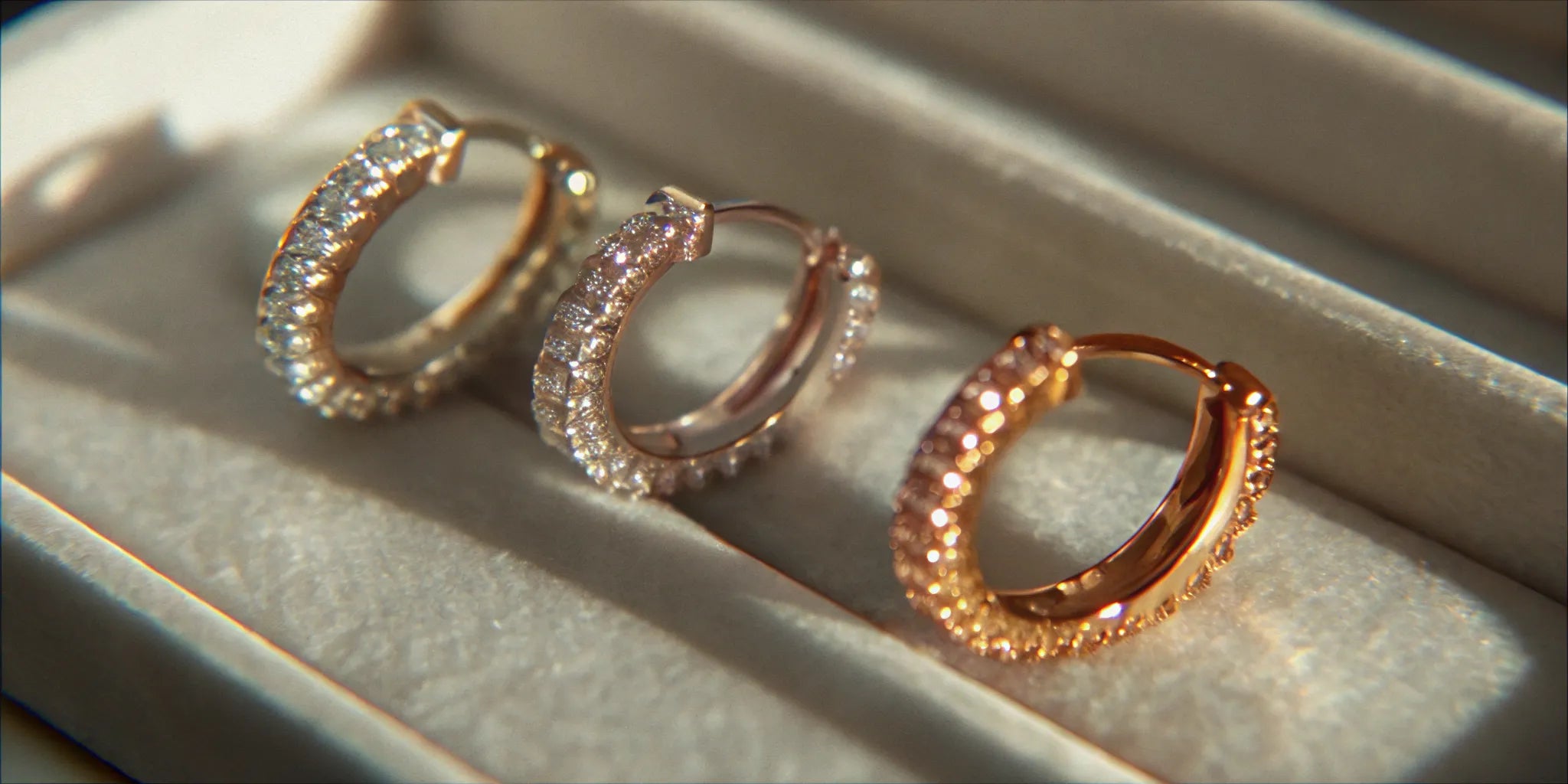 Women’s 1 carat diamond huggie earrings in gold and rose gold settings.