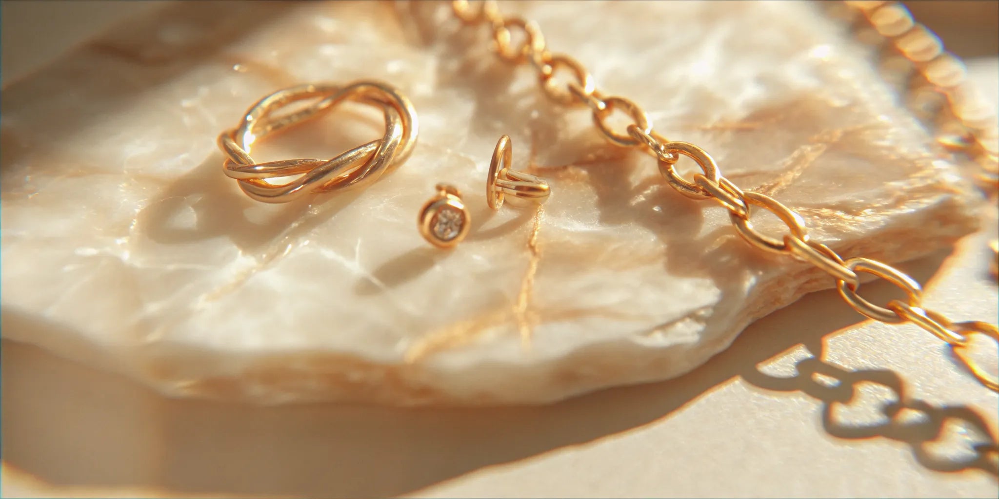 Recycled gold jewelry arranged on warm natural stone