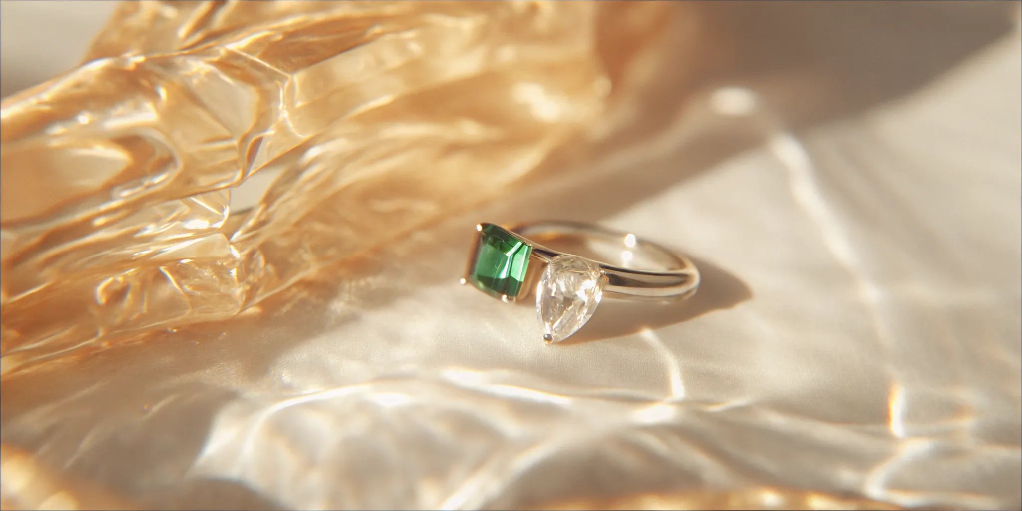 Emerald and diamond toi et moi ring with pear and emerald-cut stones.